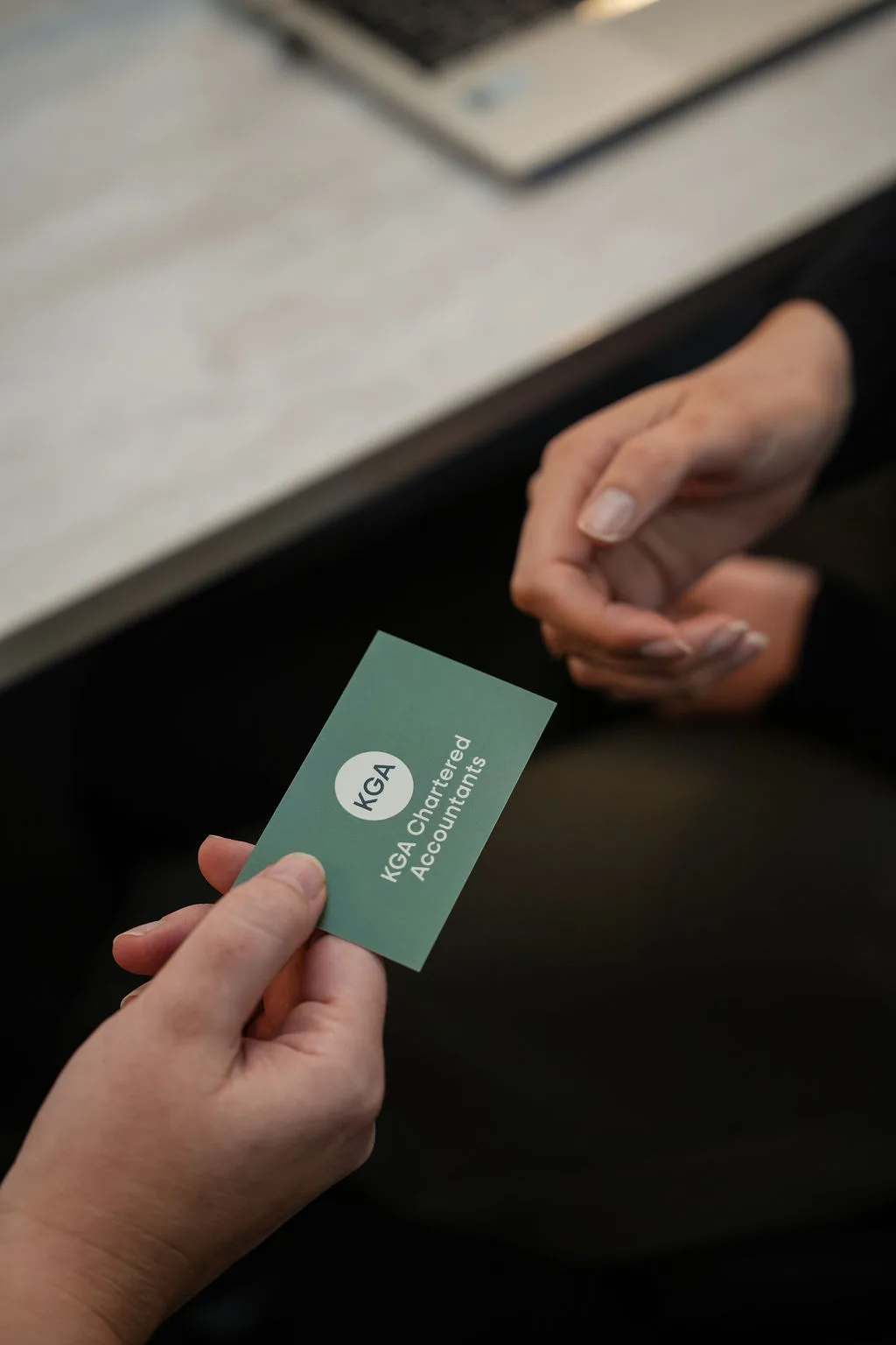 A KGA Chartered Accountants business card being handed to a client